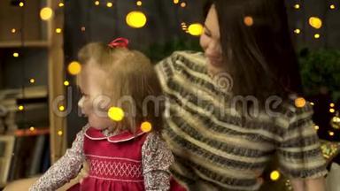 年轻的，迷人的，微笑的女人妈妈带着一个快乐的，甜美的孩子在黄色后面的美丽的新年工作室里